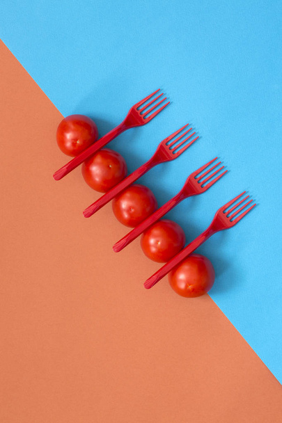 Абстрактне натюрморт з помідорами та виделками на кольоровому фоні
 - Фото, зображення