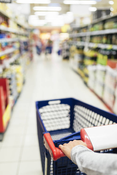 Close up of woman using shopping cart in supermarket. Background - Fotoğraf, Görsel