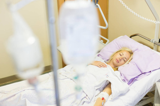 Paziente donna costretta a letto che si riprende dopo un intervento chirurgico in ospedale
. - Foto, immagini