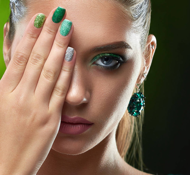 Brunette woman with shiny manicure hiding face and showing nails. - Foto, Bild