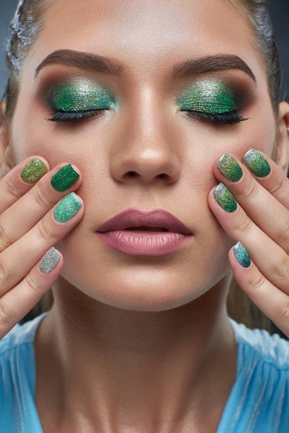 Woman with bronze skin, shiny manicure and makeup in green colors. - Photo, Image