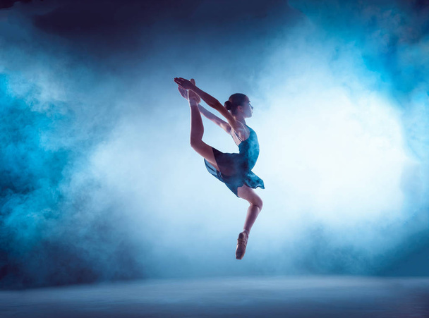 Beautiful young ballet dancer jumping on a lilac background. - Fotó, kép