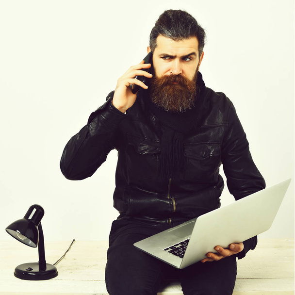 Bearded brutal caucasian hipster sitting on table with laptop - Фото, изображение