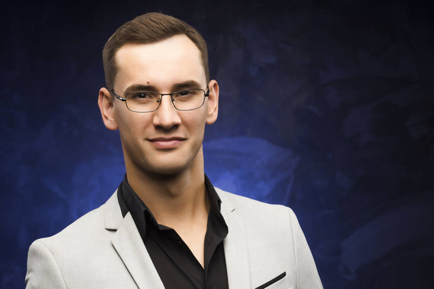 man in a gray suit and glasses on a blue background. - Foto, Bild