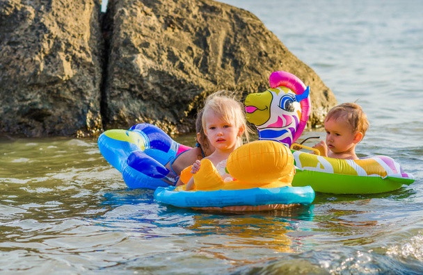 Gruppo di tre bambini nuotano in mare seduti sull'anello di gomma
. - Foto, immagini