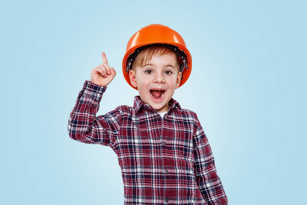 Pequeno arquiteto menino com capacete apontando para cima para copiar espaço
 - Foto, Imagem