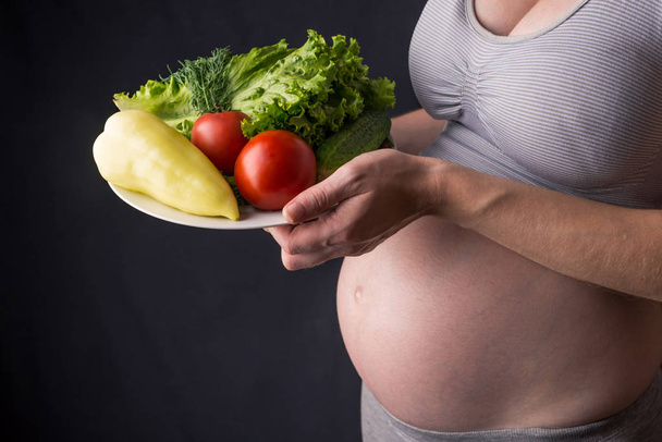 Kobieta w ciąży brzuch gospodarstwa talerz z warzywami. Koncepcja dla kontroli masy ciała i zdrowe odżywianie w ciąży - Zdjęcie, obraz