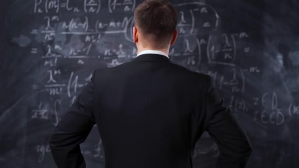 Rear view of man against chalkboard with math formula equations - Footage, Video