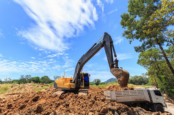 Excavator digging to moving the soil to the truck and adjusting  - Photo, Image