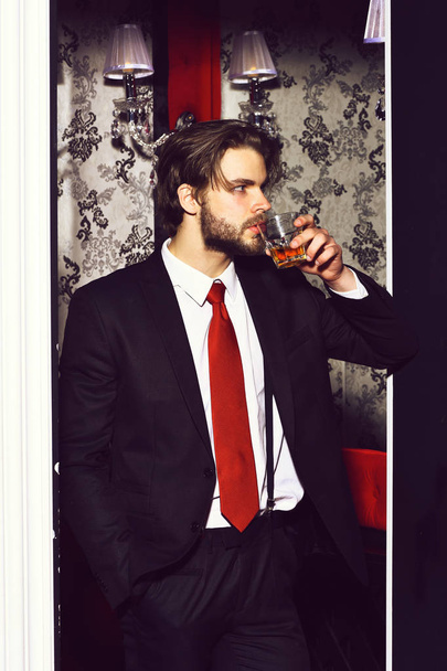 bearded man, businessman in suit, red tie holds whiskey glass - Fotoğraf, Görsel