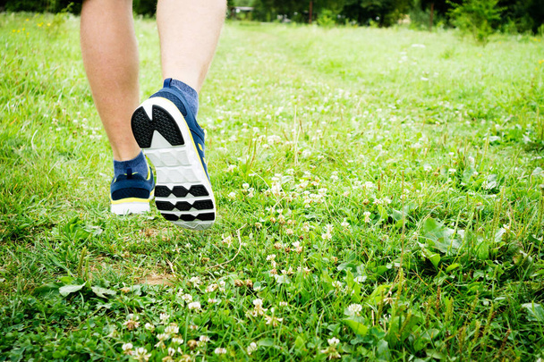 フィットネス人ランナー選手緑の芝生公園で実行しています。メンズは足実行中のクローズ アップです。スポーツ ・ ハイキング ・観光 - 写真・画像