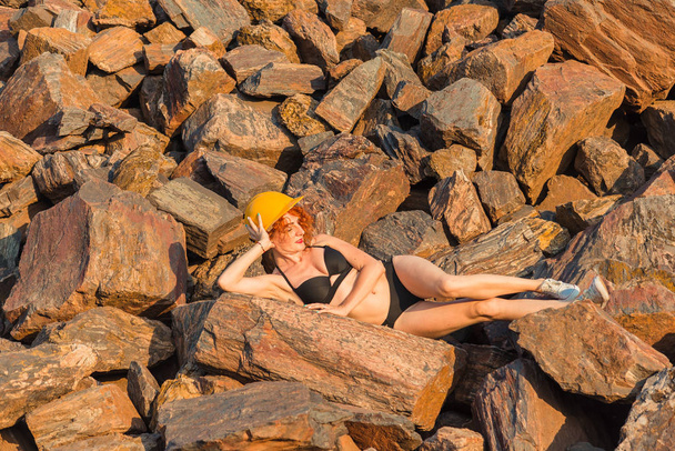 Red ore. Mountains of red ore. A girl in a swimsuit lies on a re - Foto, Imagem