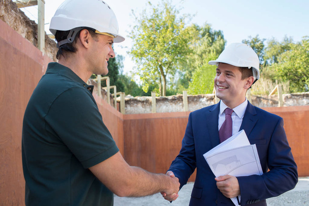 Businessman Shaking Hands With Builder On Construction Site - Foto, imagen