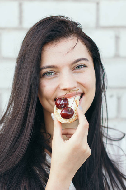 Portrait of young beautiful woman smiling with a tartlet outdoors - Foto, Bild