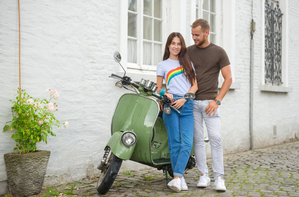 Imagem de jovem casal feliz amoroso segurando mapa ao ar livre perto de scooter. Olhando de lado
. - Foto, Imagem
