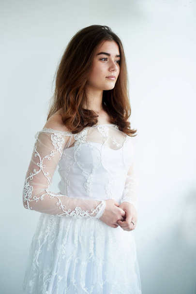 The bride on a white background in a white lace dress. Beautiful natural beauty. Light makeup and loose hair.Natural. - Foto, Bild