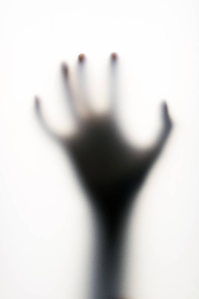 Diffused shadow of hand with thin fingers behind the frosted glass - Foto, Bild