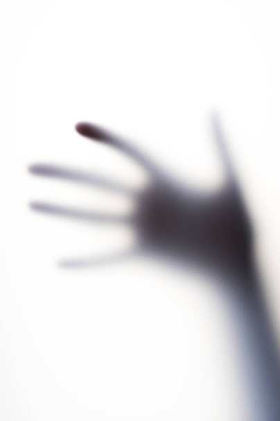 Diffused shadow of hand with thin fingers behind the frosted glass - Foto, Imagem