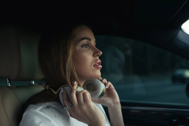 Luxury woman listen music with headphones in her comfortable car - Фото, зображення