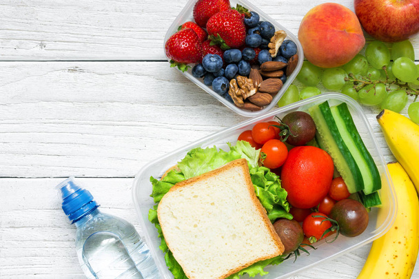 School lunch boxes with sandwich, fruits, vegetables and bottle of water and copy space - Photo, Image