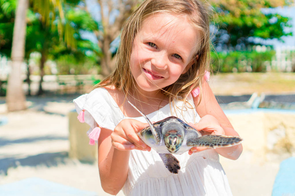 Urocza dziewczynka z małego żółwia w jej ręce, na terenie rezerwatu przyrody - Zdjęcie, obraz