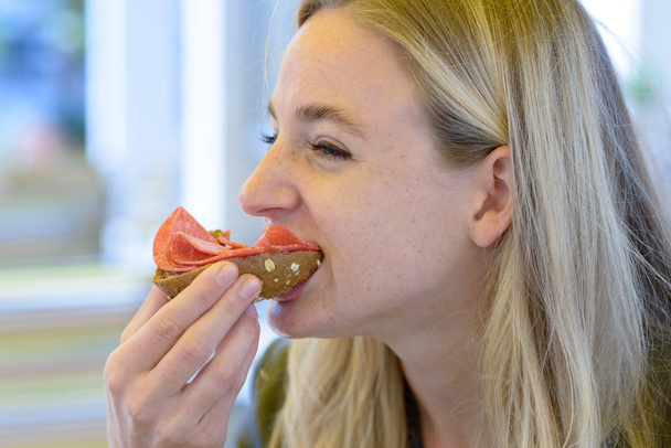 Młoda blond kobieta jedzenie kanapka - Zdjęcie, obraz