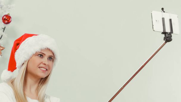 Woman in Santa hat taking Christmas selfie - Foto, imagen