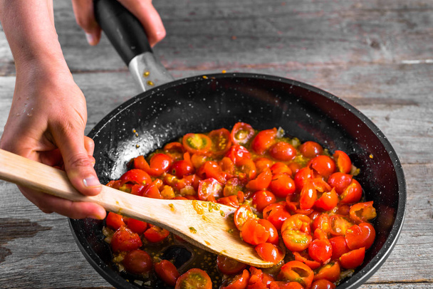 Woman cooking food for italian restaurant, making tomato sauce, mediterranean diet concept, detailed view of hands and pan with frying tomatoes - Fotografie, Obrázek