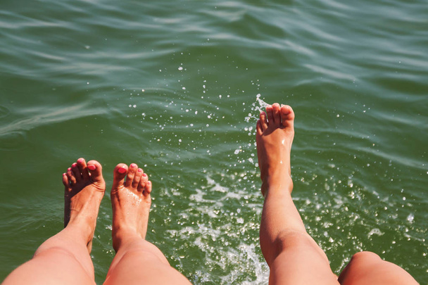 Zwei Paar Füße planschen im Wasser - Foto, Bild