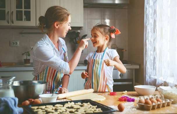 Happy family mother and daughter bake kneading dough in kitche - Photo, Image