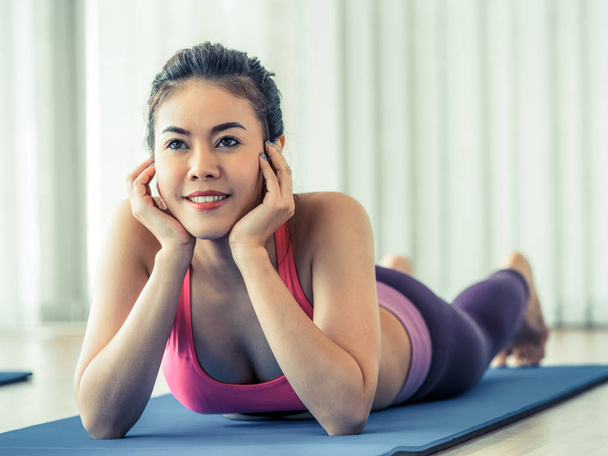 Young happy woman relaxing on yoga mat in gym - Fotó, kép