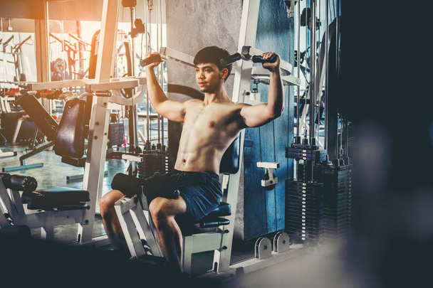 Fitness man exercising at the gym on a machine strong bodybuilde - Valokuva, kuva