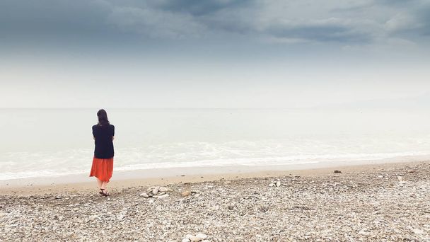 Молода жінка йде сама в босоніж на березі
 - Фото, зображення