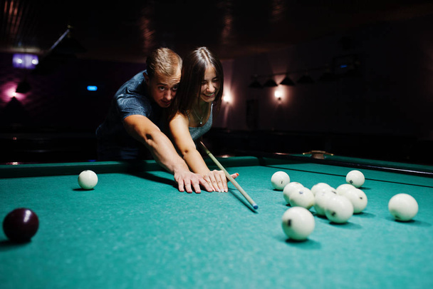 Woman in dress playing pool with a man in a pub. - Zdjęcie, obraz