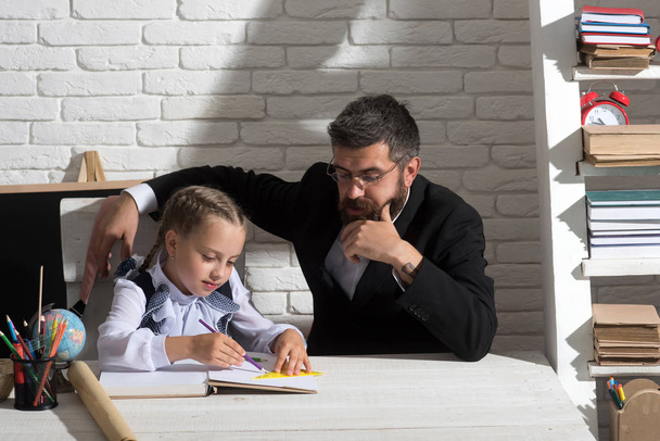 Schoolgirl and her dad with thoughtful faces write in notebook - Foto, Imagen
