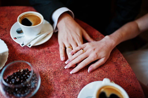Close-up photo of a wedding couple holding hands in a small cafe - Foto, imagen