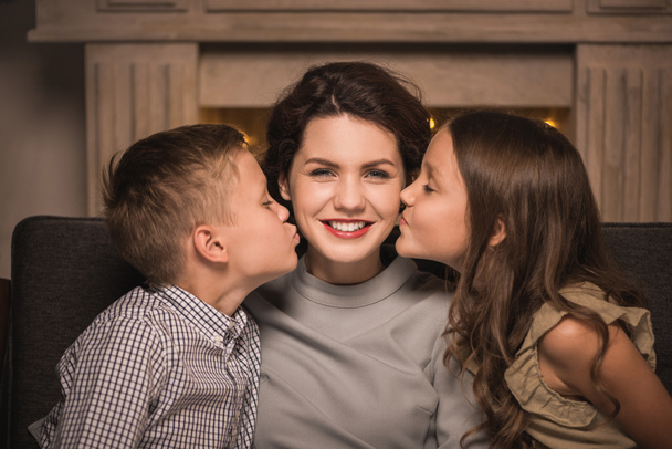 Дети целуют улыбающуюся мать
 - Фото, изображение