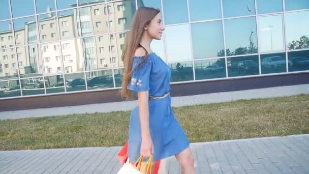 Νεαρή γυναίκα, που μεταφέρουν τσάντες για ψώνια, ενώ το περπάτημα κατά μήκος του δρόμου - Πλάνα, βίντεο