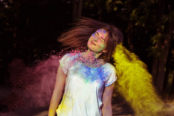 Young brunette woman playing with dry powder Holi - Foto, imagen