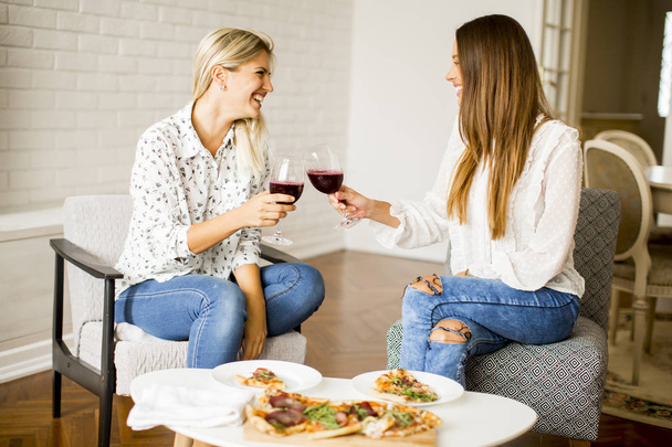 hübsche junge Frauen essen Pizza und trinken Rotwein - Foto, Bild