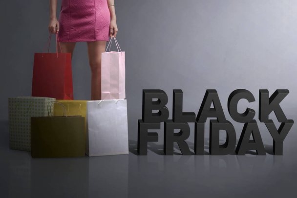 Young shopper holding shopping bag standing with Black Friday te - Foto, Bild