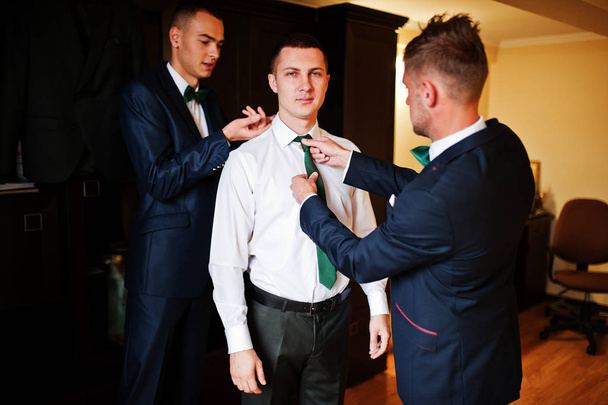 Groomsmen helping groom to dress up and get ready for his weddin - Zdjęcie, obraz