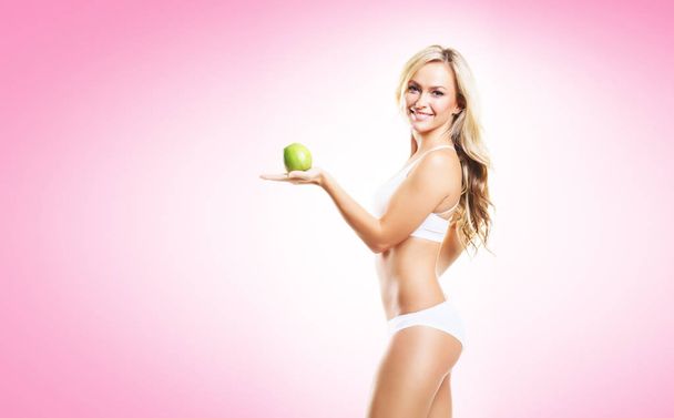 woman in white lingerie with green apple - Фото, изображение