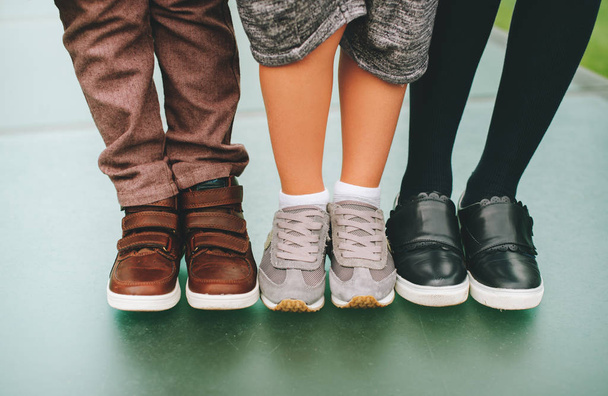 Zapatos de moda para niños. Tres pares de pies de niños con zapatillas cómodas y de moda. Regreso al concepto escolar
 - Foto, imagen
