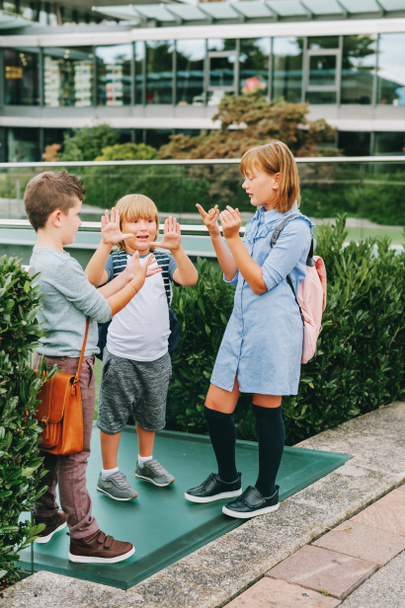 Group of 3 kids playing Rock, Paper, Scissors game on schoolyard. Back to school concept, fashion for children - Foto, Imagem