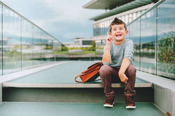 Outdoor portrait of happy young kid boy. Fashion schoolboy resting outside. Back to school concept - Photo, Image