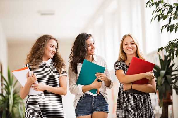 Three teenage girls in high school hall during break. - Fotografie, Obrázek