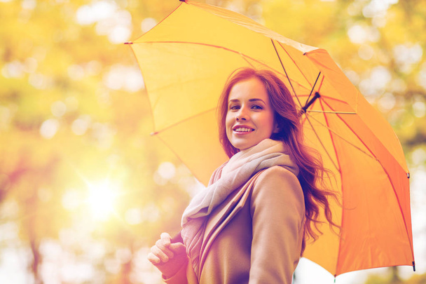happy woman with umbrella walking in autumn park - 写真・画像