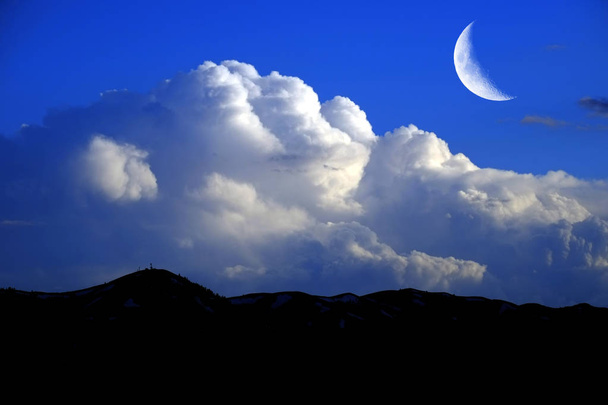 Bergen sky golvende witte donder wolken en wassende maan - Foto, afbeelding