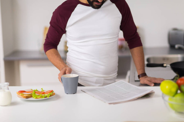 man reading newspaper and eating at home kitchen - Photo, Image